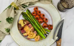 Ossenhaas tournedos met knoflookgarnalen roomsaus, gegrilde asperges en geroosterde tomaatjes