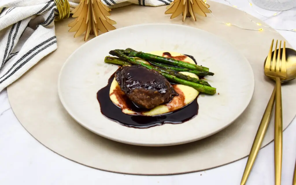 Krokantgebakken varkenswangetjes uit de sous vide met polenta, rode wijn-portsaus en aspergetips