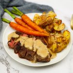 Ribeye steak met pepersaus, smashed potatoes en gebakken worteltjes