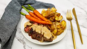 Ribeye steak met pepersaus, smashed potatoes en gebakken worteltjes