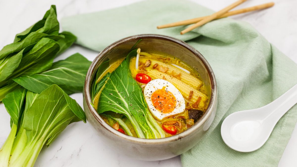 Gele currysoep met noedels, bok choy en een gekookt eitje
