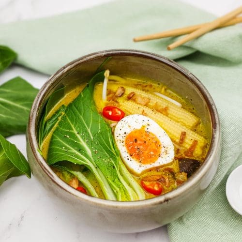 Gele currysoep met noedels, bok choy en een gekookt eitje
