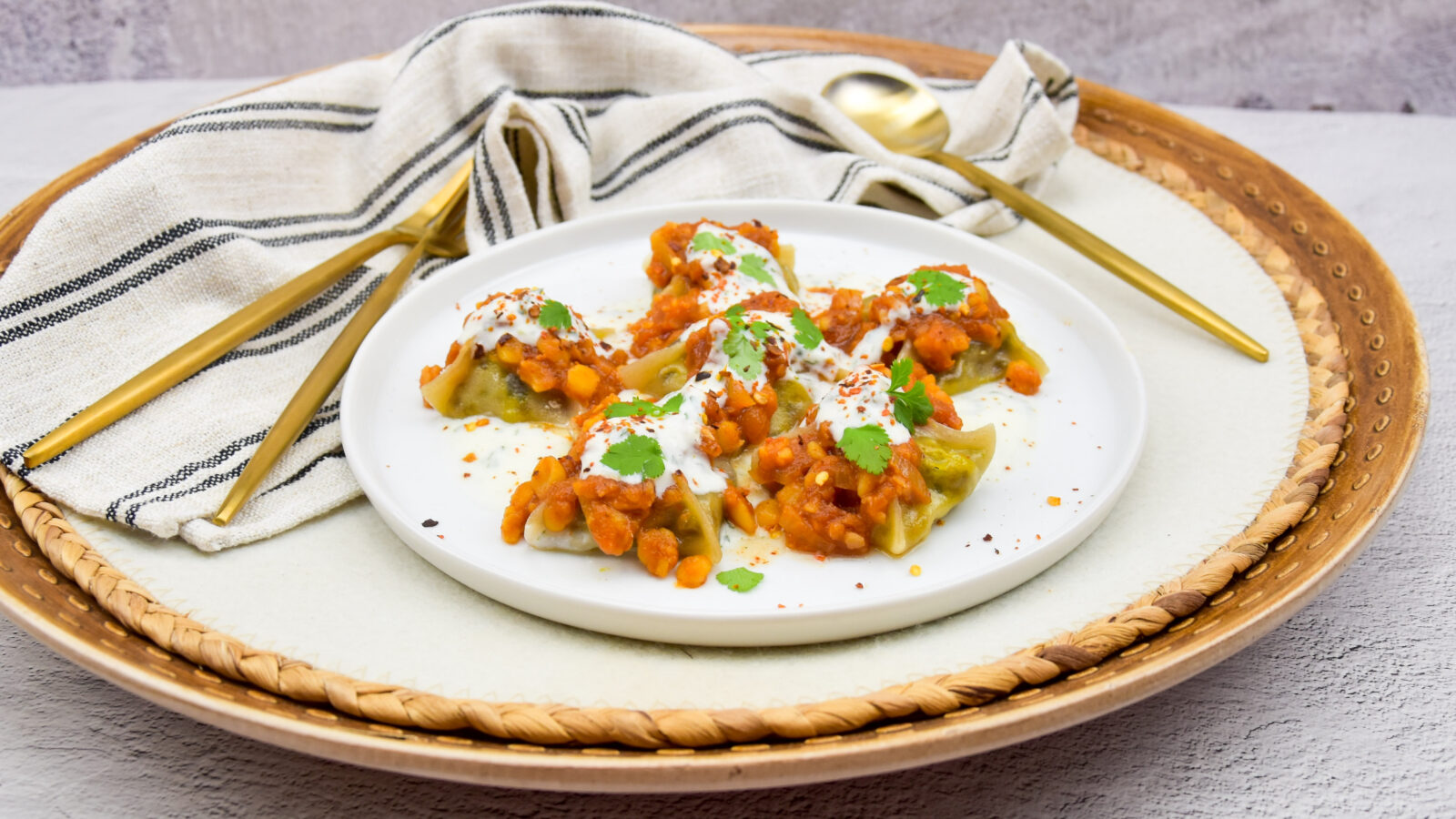 Manti (of mantu) met yoghurtsaus, tomatensaus en gele spliterwten