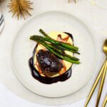 Krokantgebakken varkenswangetjes uit de sous vide met polenta, rode wijn-portsaus en aspergetips