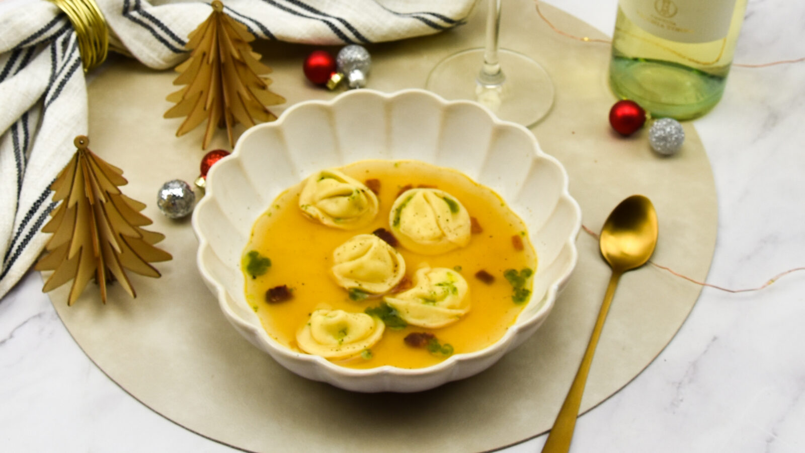 Tomatenconsommé met burrata tortellini, uitgebakken guanciale en basilicum olie